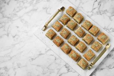 Photo of Delicious fresh baklava with chopped nuts on white marble table, top view and space for text. Eastern sweets