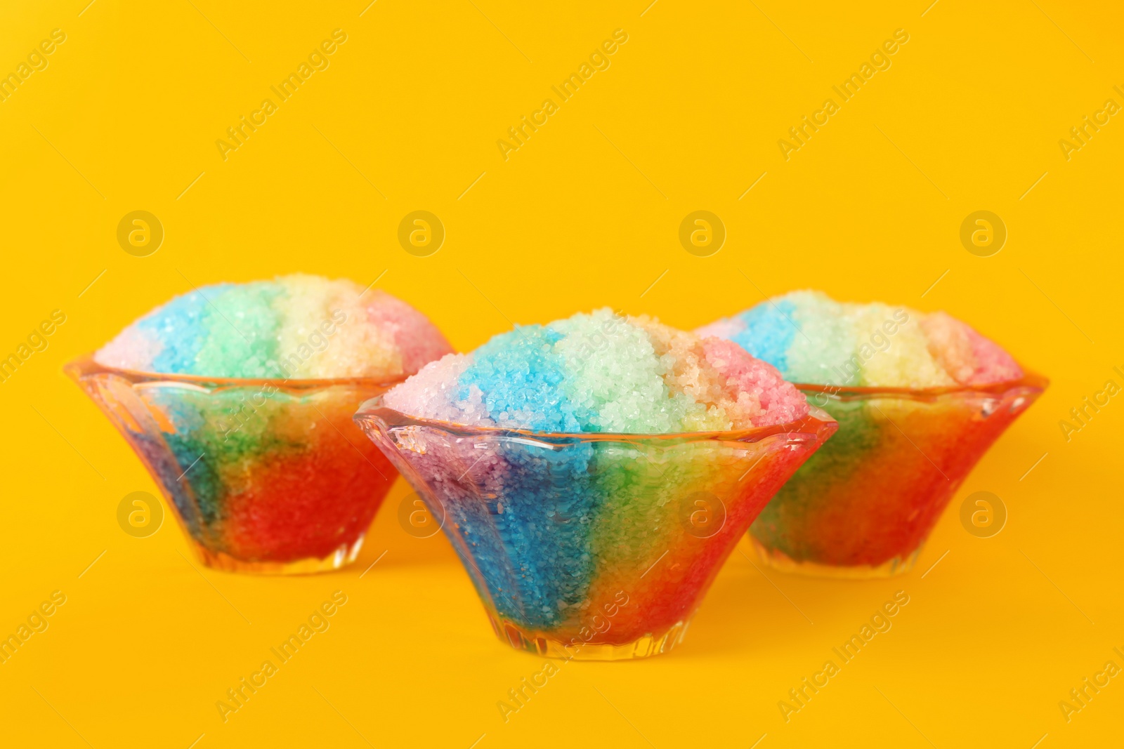 Photo of Rainbow shaving ice in glass dessert bowls on orange background