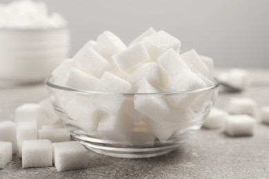 Photo of Bowl with sugar cubes served on grey table, closeup