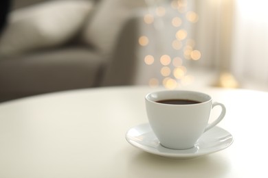 Photo of Cup of coffee on table indoors, space for text. Bokeh effect