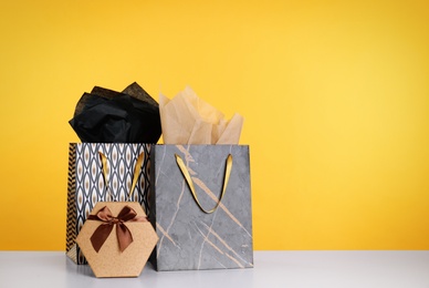 Photo of Shopping bags and gift box on yellow background. Space for text