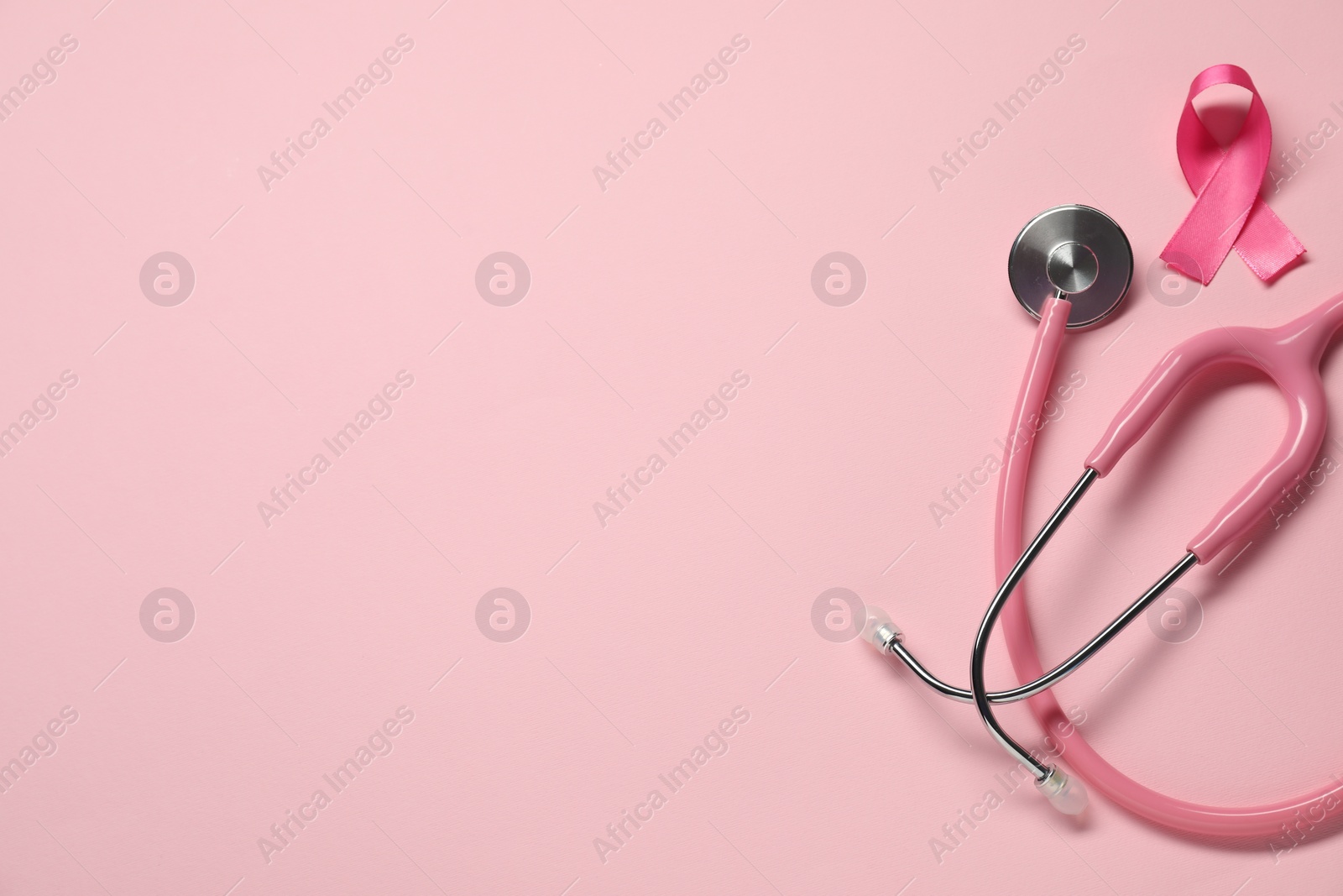 Photo of Breast cancer awareness. Pink ribbon and stethoscope on color background, flat lay. Space for text