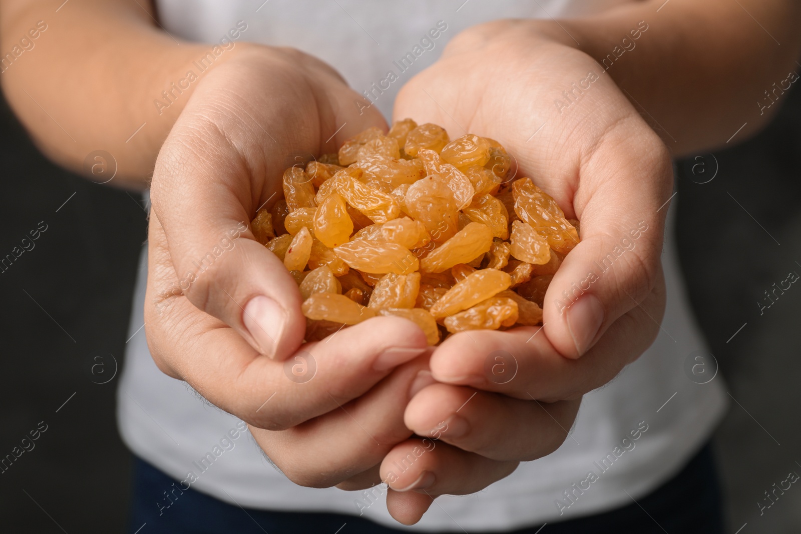 Photo of Woman holding raisins on black background, closeup