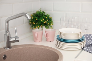 Photo of Clean dishes on counter near kitchen sink indoors