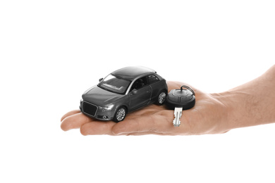 Man holding key and miniature automobile model on white background, closeup. Car buying