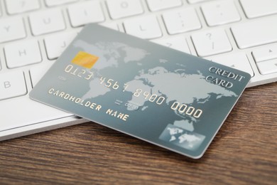 Photo of Online payment concept. Bank card and computer keyboard on wooden table, closeup