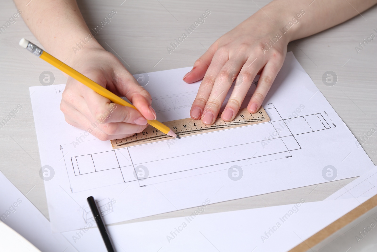 Photo of Woman creating packaging design at light wooden table, closeup