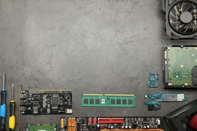 Photo of Graphics card and other computer hardware on grey textured table, flat lay. Space for text