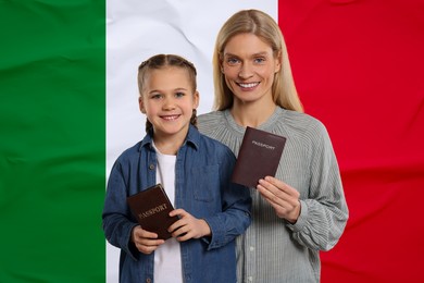 Image of Immigration. Happy woman and her daughter with passports against national flagItaly