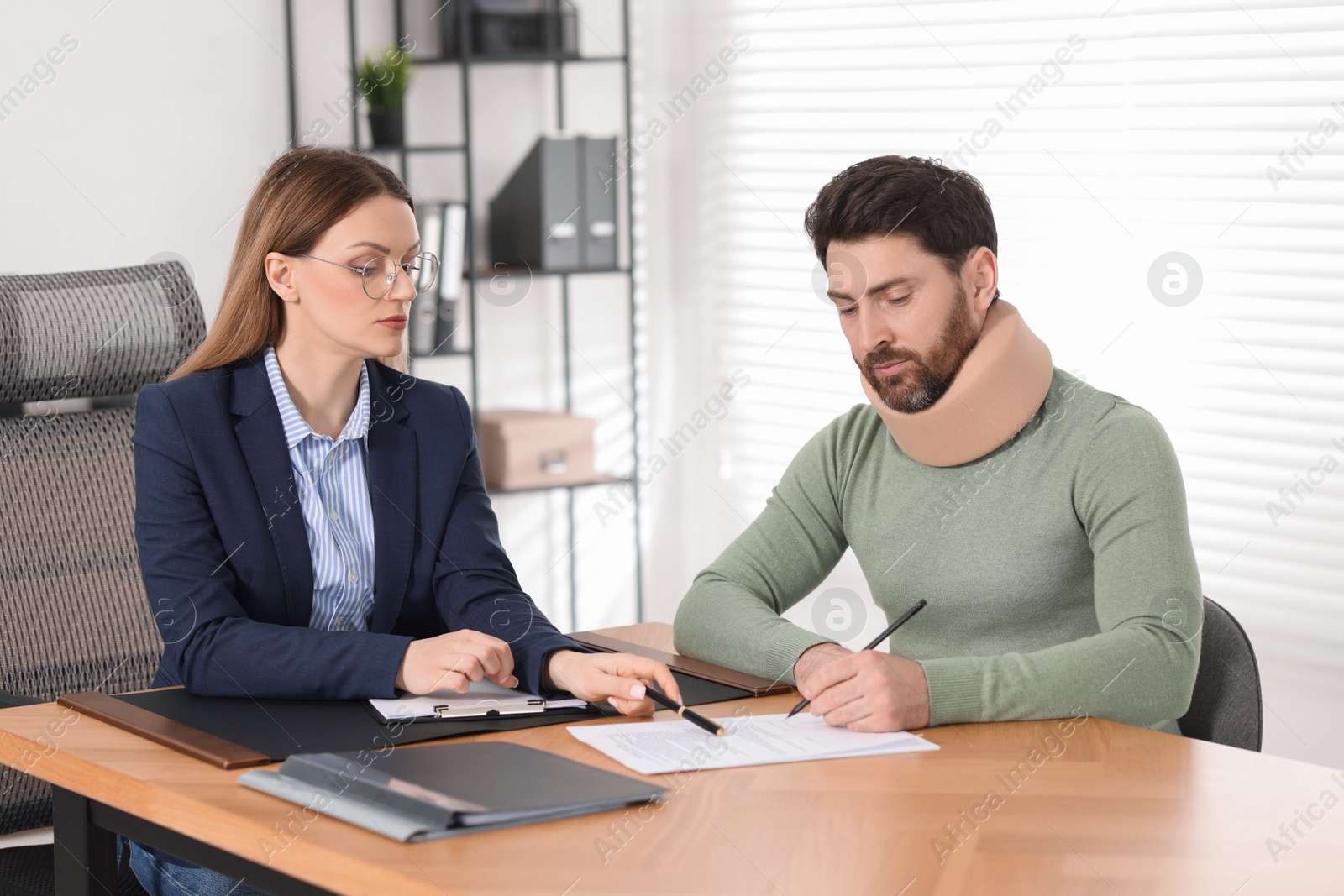 Photo of Injured man signing document in lawyer's office