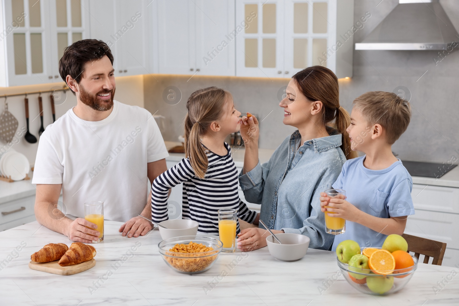 Photo of Happy family having breakfast at table in kitchen