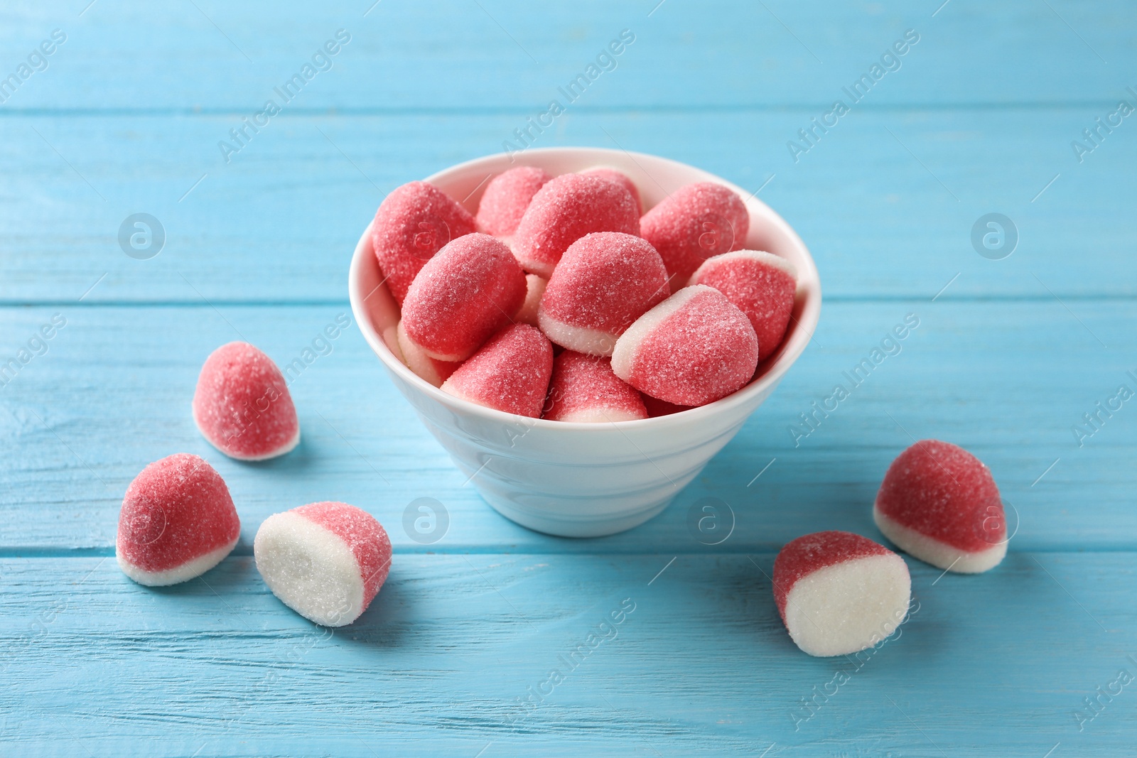 Photo of Bowl of tasty jelly candies on blue wooden table