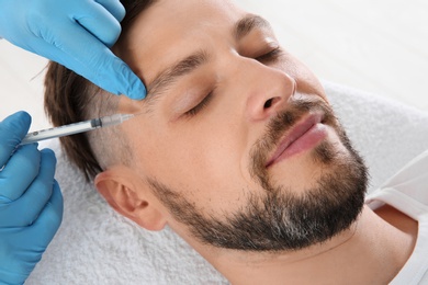 Photo of Man getting facial injection in clinic. Cosmetic surgery concept