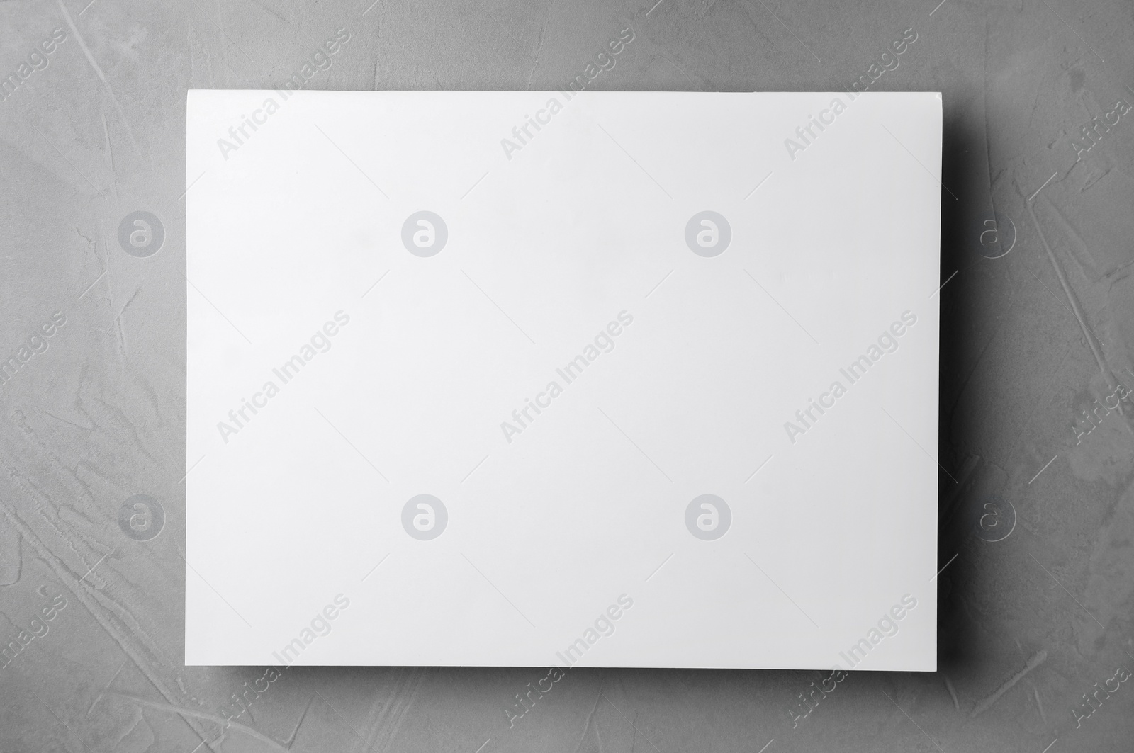 Photo of Blank paper sheets on light grey stone background, top view. Mock up for design