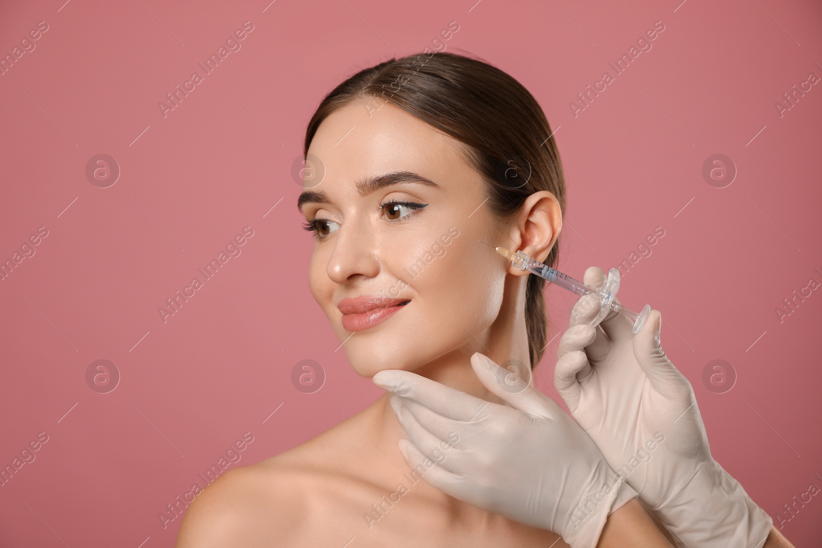 Photo of Beautiful woman getting facial injection on pink background. Cosmetic surgery