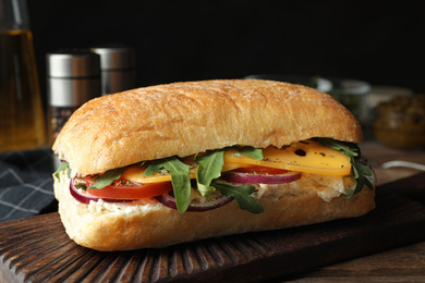 Photo of Delicious sandwich with fresh vegetables and cheese on wooden table