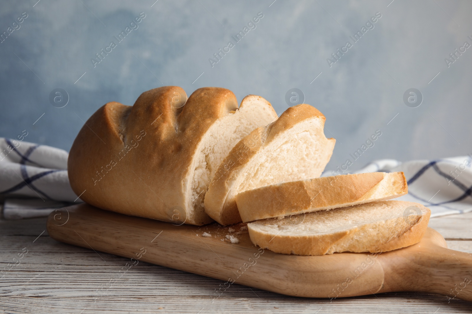 Photo of Board with tasty wheat bread on table