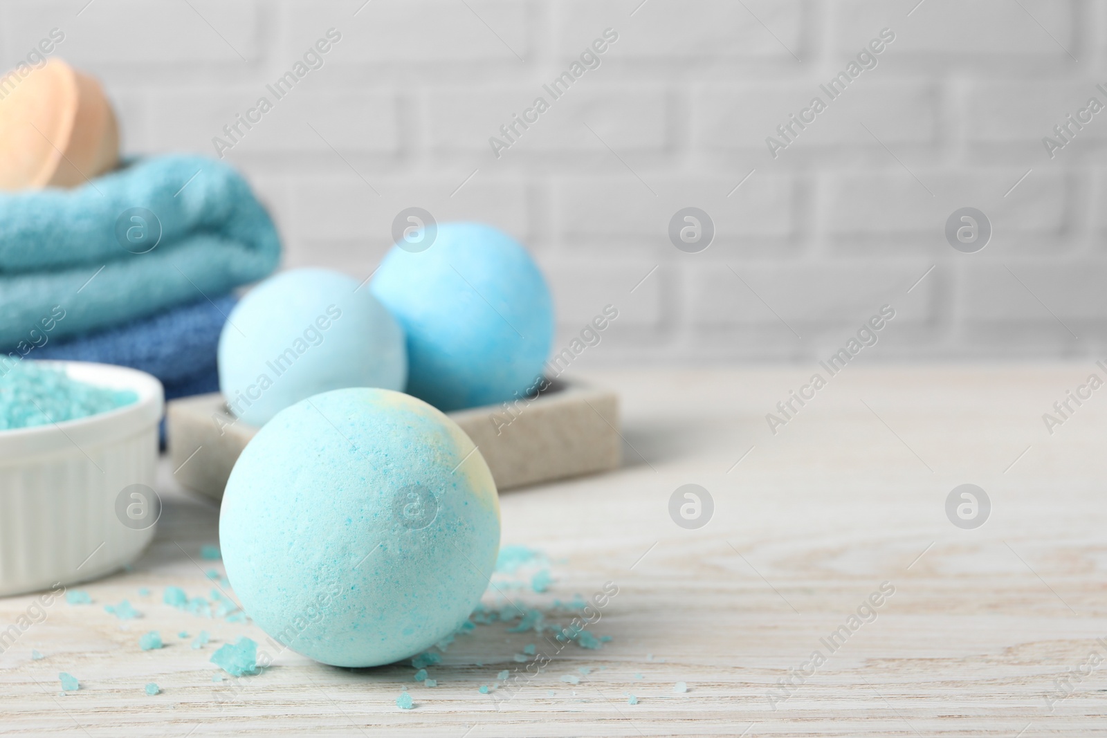 Photo of Beautiful aromatic bath bombs and sea salt on light wooden table. Space for text