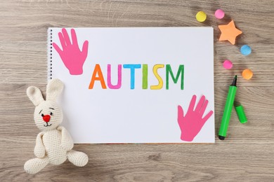 Photo of Flat lay composition of notebook with word Autism and toys on wooden table