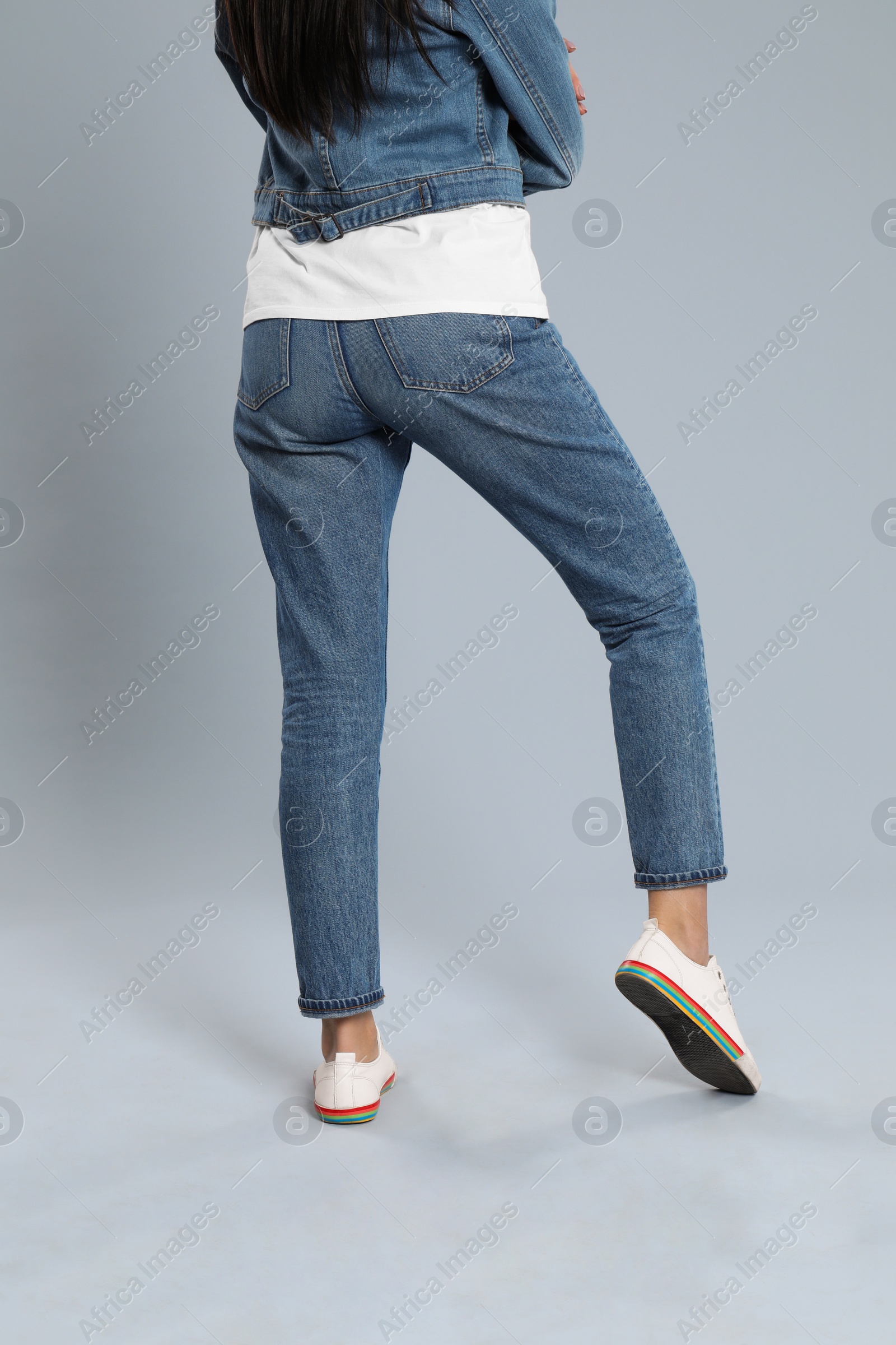 Photo of Young woman in stylish jeans on grey background, closeup