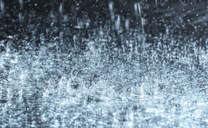 Photo of Heavy rain falling down on ground against dark background