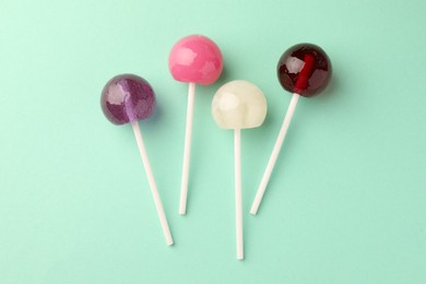 Photo of Tasty lollipops on turquoise background, flat lay