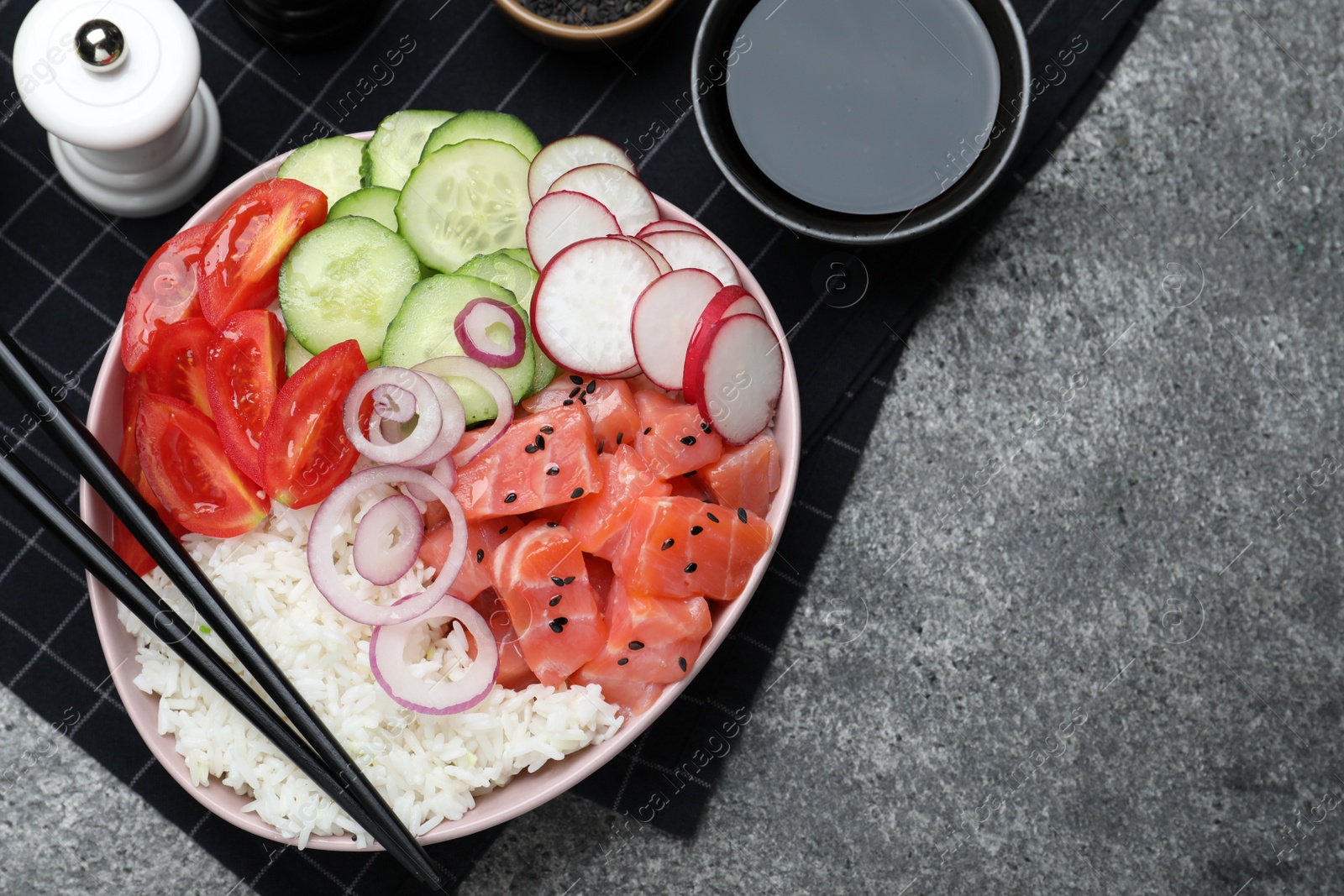 Photo of Delicious poke bowl with salmon and vegetables served on grey table, flat lay. Space for text