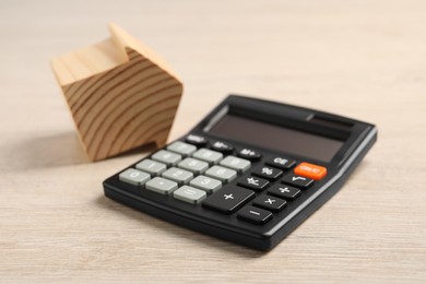 Photo of Mortgage concept. House model and calculator on wooden table, closeup