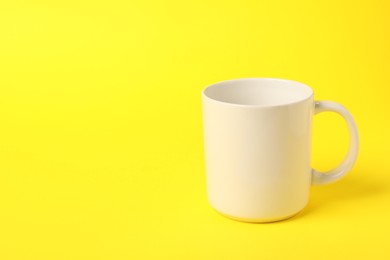 Photo of One white ceramic mug on yellow background, space for text