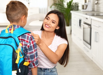 Photo of Happy mother and little child with backpack ready for school in kitchen