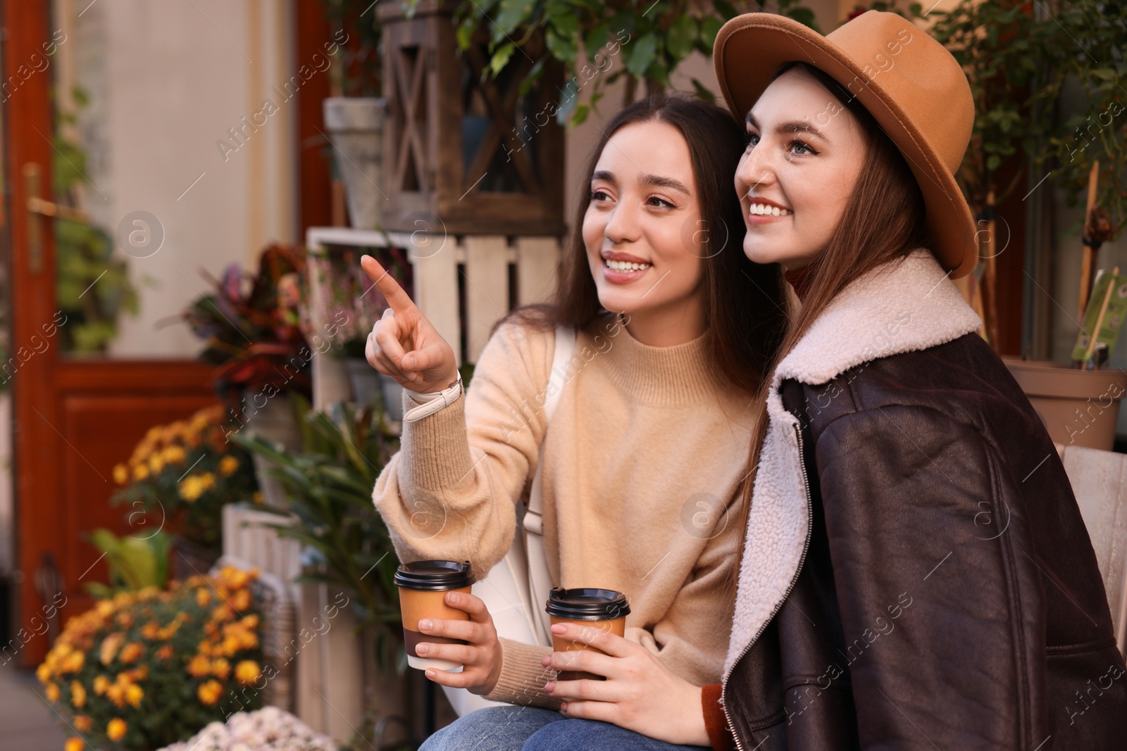 Photo of Happy friends with paper cups of coffee outdoors