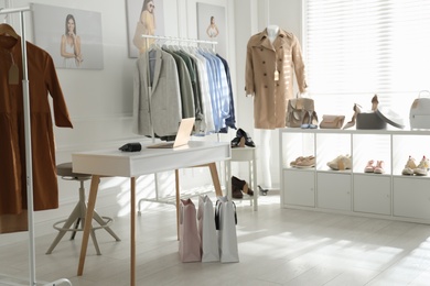 Collection of stylish women's clothes, shoes and accessories in modern boutique