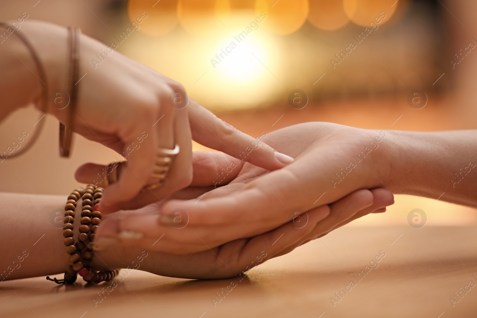 Photo of Chiromancer reading lines on woman's palm at table, closeup