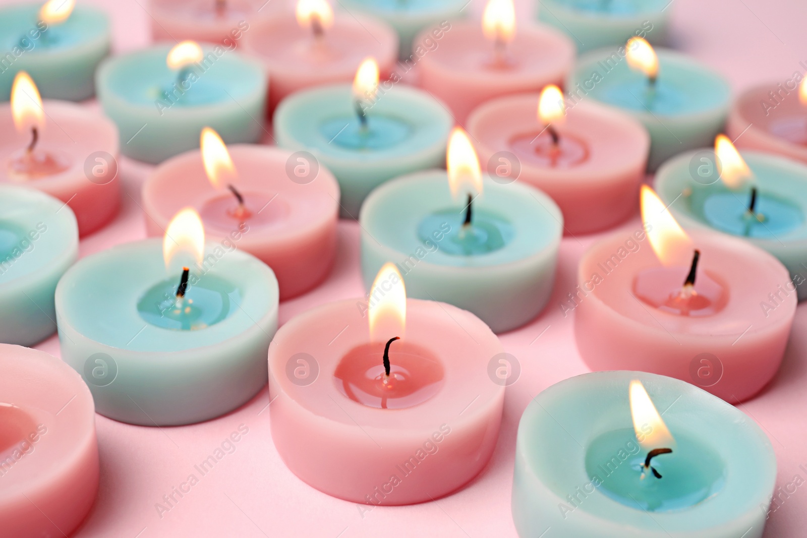 Photo of Burning colorful decorative candles on pink background, space for text