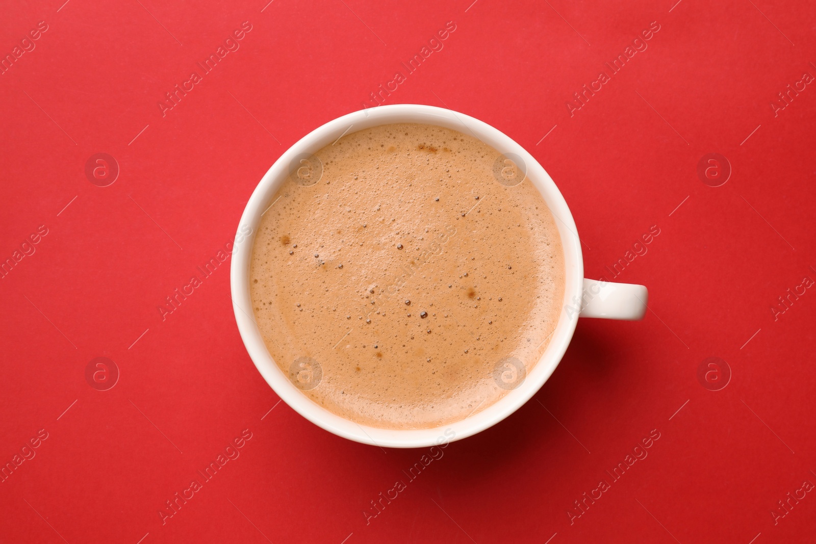 Photo of Fresh coffee in cup on red background, top view