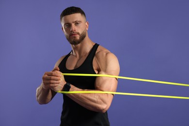 Muscular man exercising with elastic resistance band on purple background