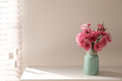 Photo of Bouquet of beautiful Eustoma flowers on table near light wall. Space for text