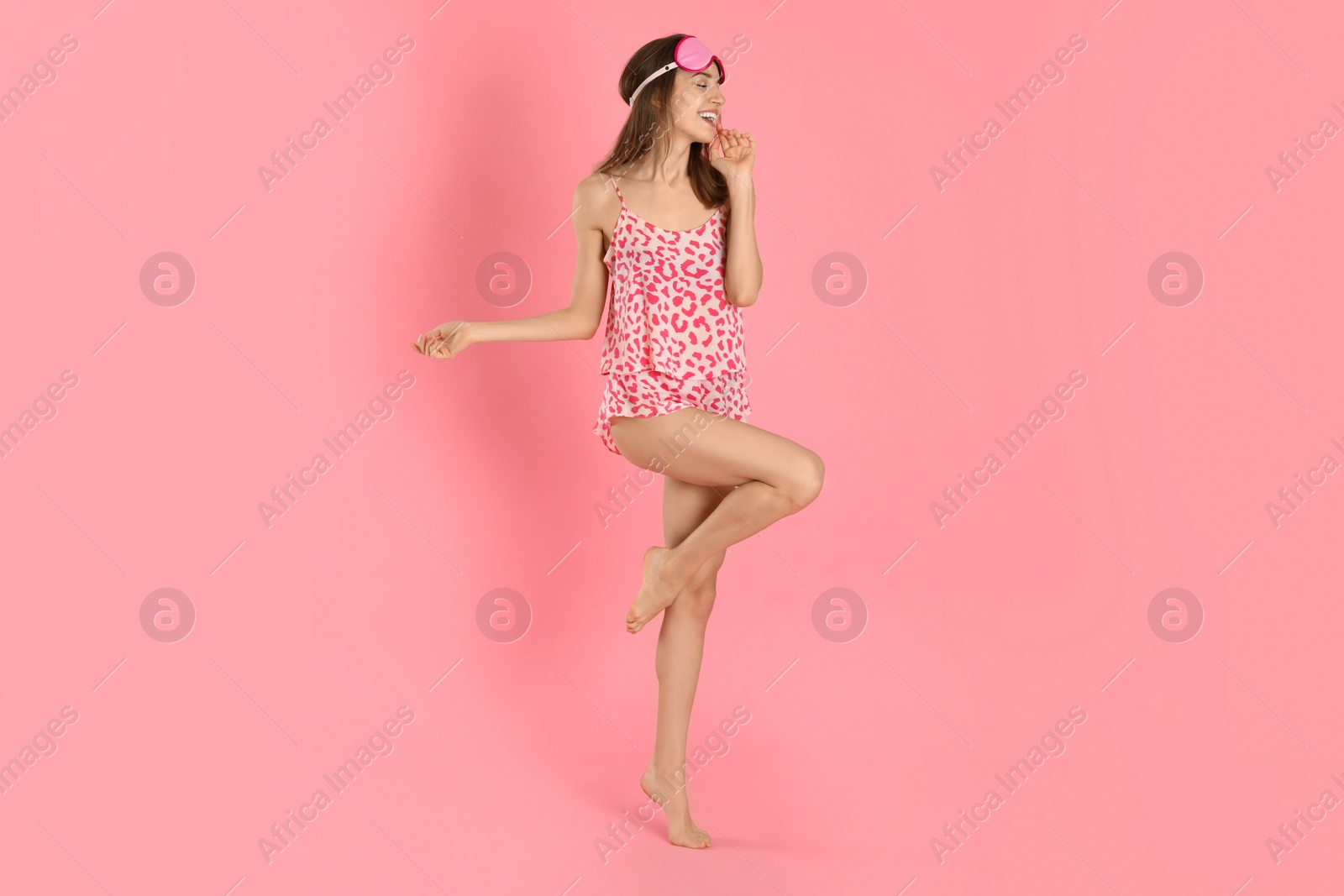 Photo of Beautiful woman wearing pajamas and sleep mask on pink background. Bedtime