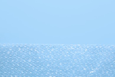 Photo of Transparent bubble wrap on light blue background, top view. Space for text