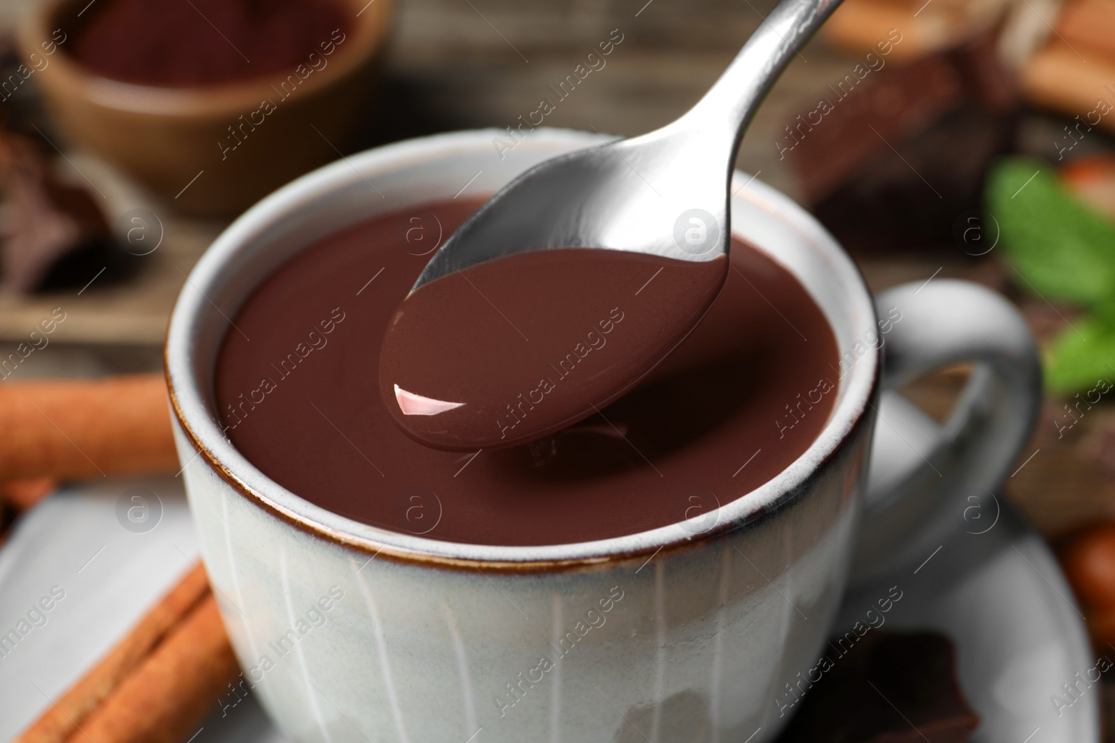 Photo of Spoon with yummy hot chocolate over cup, closeup