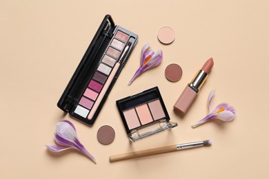 Flat lay composition with different makeup products and beautiful flowers on beige background