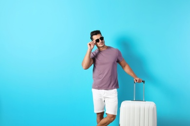 Photo of Young man with suitcase on color background