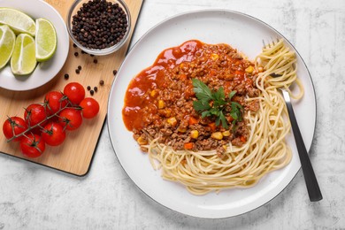 Tasty dish with fried minced meat, spaghetti, carrot and corn served on white textured table, flat lay