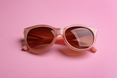 Photo of Stylish sunglasses on pink background. Fashionable accessory