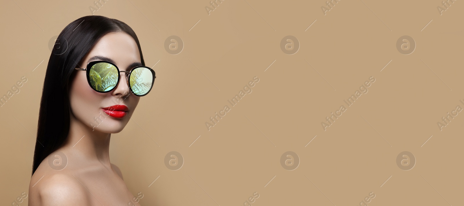 Image of Attractive woman in stylish sunglasses on dark beige background, space for text. Palm leaves and sky reflecting in lenses. Banner design