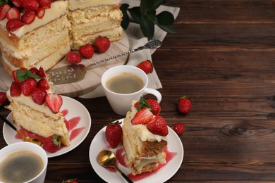 Tasty cake with fresh strawberries, mint and cups of coffee on wooden table. Space for text