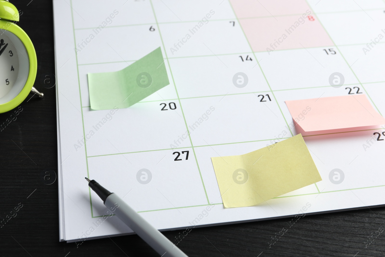 Photo of Timetable. Planner with sticky notes and pen on black wooden table, closeup