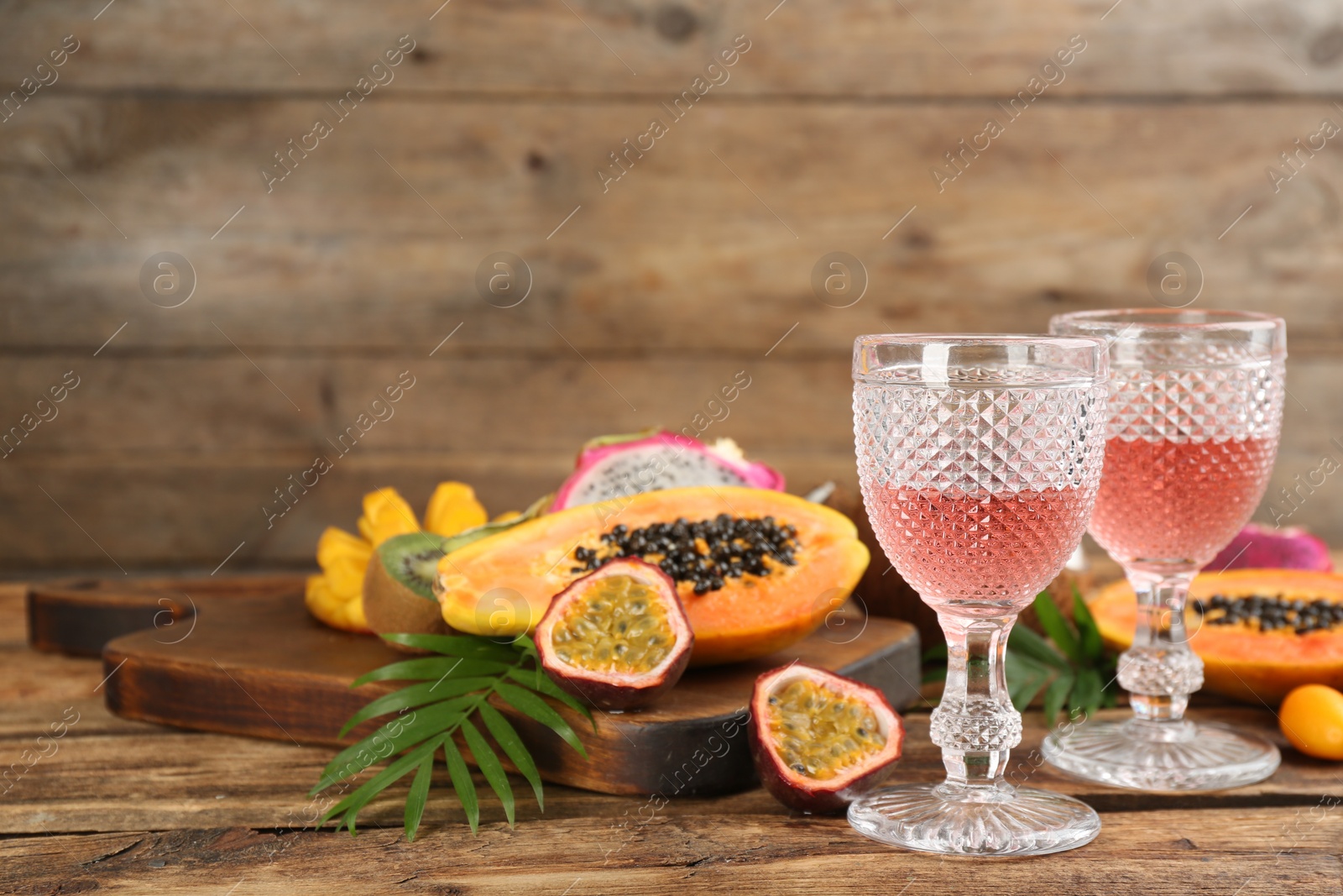 Photo of Delicious exotic fruits and wine on wooden table