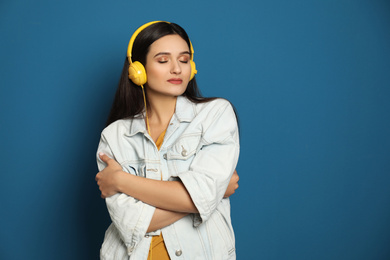 Photo of Young woman listening to audiobook on blue background. Space for text