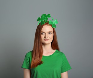 Image of St. Patrick's day party. Pretty woman with green clover headband on grey background